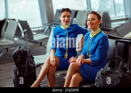 Fröhliche Frauen Stewardessen warten auf den Flug am Flughafen Stockfoto