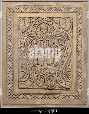 Dado-Tafel 10th Jahrhundert die ursprüngliche Platzierung dieser einzigartigen Stuckplatte ist ungewiss, obwohl ihre Form und Größe darauf hindeutet, dass sie einen Dado oder die untere Hälfte einer Wand schmückte. Es wurde in fragmentarischer Form auf dem Boden eines Hofes gefunden, der in dem Hügel Sabz Pushan (der grüne bedeckte) in Nishapur ausgegraben wurde, nachdem er Jahrhunderte zuvor von einer nahe gelegenen Mauer zerbröckelt war. Zusätzlich zu seiner reich geschnitzten Dekoration einer dreilappigen Nische, hatte diese Tafel einst helle Farben. Spuren von gelbem Pigment wurden auf dem nicht geschnitzten Band gefunden, das die Hauptszene umrahmt. Andere geschnitzte und bemalte Ornamente Stockfoto