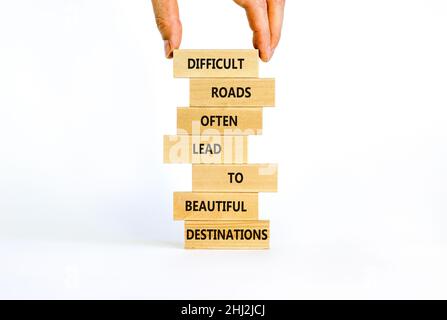 Motivationssymbol. Blöcke mit Worten schwierige Straßen führen oft zu schönen Zielen. Schöner weißer Hintergrund, Kopierbereich. Geschäftsmann Hand. Stockfoto