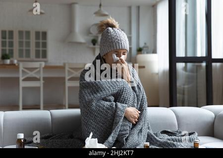 Kranke Frau mit karierten, laufenden Nase in Serviette geblasen Stockfoto