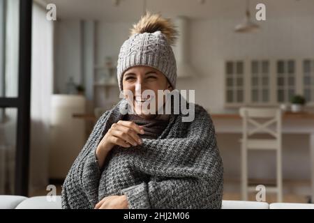 Lachende Frau tragen Hut in gestricktem Karli gewickelt sitzen drinnen Stockfoto