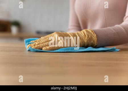 Nahaufnahme weibliche Hand in Handschuh Reinigung hölzerne Arbeitsplatte mit Lappen Stockfoto