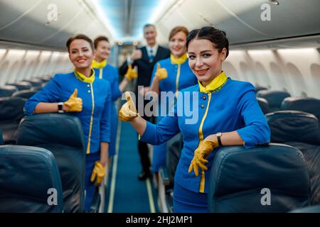 Mitarbeiter von Fluggesellschaften zeigen in der Passagierkabine des Flugzeugs eine Geste der Genehmigung Stockfoto