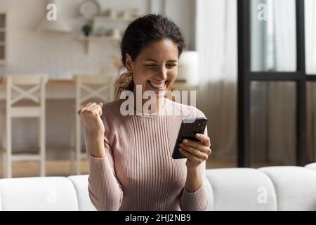 Frau lesen Nachrichten auf Handy fühlt sich glücklich bekam unglaubliches Angebot Stockfoto