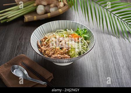 Gebratene Lemongrass Beef Dry Noodle in einer Schüssel auf einem Holztisch umrühren Stockfoto