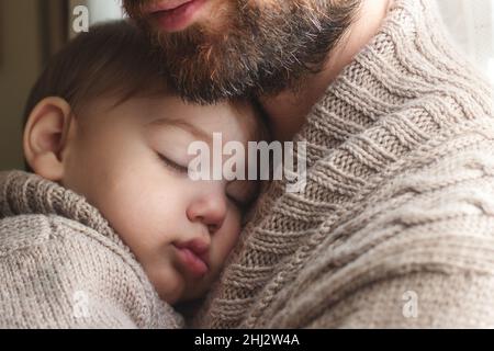 Vater hält ein kleines Kleinkind, das in seinen Armen schläft Stockfoto