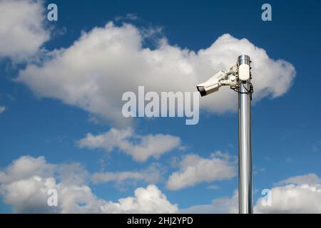 cctv-Überwachungskameras für den Außenbereich auf einer Stange mit blauem, bewölktem Himmel. Stockfoto