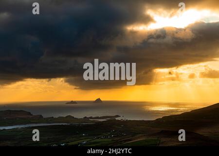 Meeresküste mit den Berggipfeln der Skelligs im Hintergrund und dramatisch bewölktem Himmel, Killarny, County Kerry, Irland Stockfoto