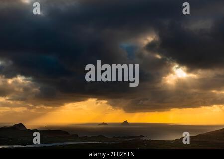 Meeresküste mit den Berggipfeln der Skelligs im Hintergrund und dramatisch bewölktem Himmel, Killarny, County Kerry, Irland Stockfoto