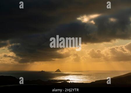 Meeresküste mit den Berggipfeln der Skelligs im Hintergrund und dramatisch bewölktem Himmel, Killarny, County Kerry, Irland Stockfoto