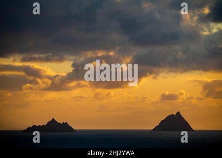 Meeresküste mit den Berggipfeln der Skelligs im Hintergrund und dramatisch bewölktem Himmel, Killarny, County Kerry, Irland Stockfoto