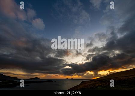 Meeresküste mit den Berggipfeln der Skelligs im Hintergrund und dramatisch bewölktem Himmel, Killarny, County Kerry, Irland Stockfoto