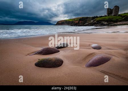 Sandstrand mit Steinen und Minard Castle im Hintergrund, Dingle Peninsula, Kerry, Irland Stockfoto