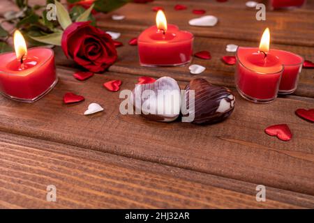 Valentinstag Konzept Schokolade Bonbons herzförmig und rote Rosen mit Kerzen auf Holz. Liebe und Romantik Konzept. Stockfoto