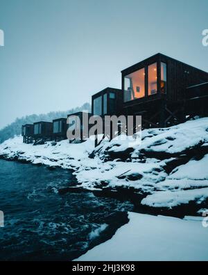 Winziges Haus oder Hütte am Ufer des Ozeans. Winterblick über die Fjorde in Norwegen Skandinavien. Luxusreisen Stockfoto