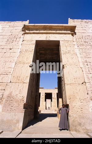 Ägyptischer Mann, der vor dem Tempel von Ramses III, Luxor, Ägypten, steht Stockfoto