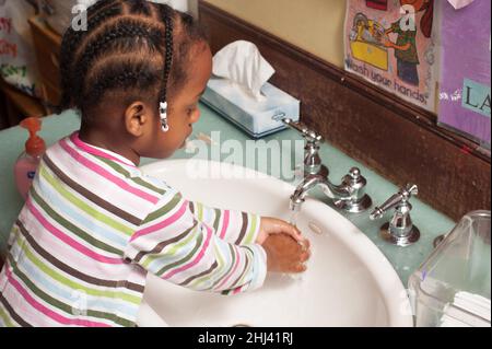 Bildung Vorschule Mädchen im Alter von 3-4 Jahren, das sich am Waschbecken die Hände wusch Stockfoto