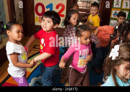 Bildung Vorschule 3-4-jährige Gruppe von Jungen und Mädchen tanzen zu Musik Stockfoto