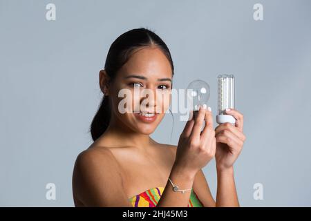 Junges Mädchen mit Glühbirne in ihrem Mann mit niedrigem und hohem Stromverbrauch Stockfoto