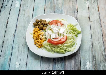 Der Salat kombiniert kaltes Gemüse (wie Salat, Rucola oder Spinat) und verschiedene gehackte Gemüse, gemischt und gewürzt mit Salz, Pflanzenöl A Stockfoto