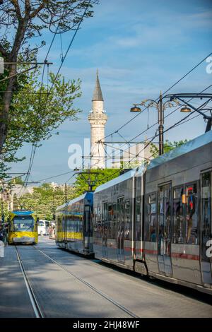 Istanbuler Innenstadt Straße mit Straßenbahnen und Moschee Minarett im Hintergrund Stockfoto