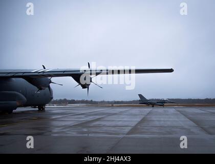 Eine belgische F-16 taxt am 24. Januar 2022 an einer C-130J Super Hercules vorbei, die dem Luftlift-Flügel 86th des Flugstützpunkts Ramstein, Deutschland, auf dem Luftwaffenstützpunkt Ämari, Estland, zugewiesen wurde. Die C-130J und F-16 unterstützen eine NATO-verstärkte Luftpolizierungsmission. Die verstärkte Luftpolizei demonstriert die Solidarität, den kollektiven Willen und die Fähigkeit der NATO, ihre Verteidigungsmissionen und ihre Abschreckungshaltung als Reaktion auf die sich entwickelnde Sicherheitssituation, vor der das Bündnis steht, anzupassen und zu skalieren. (USA Luftwaffe Foto von Staff Sgt. Megan Beatty) Stockfoto