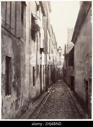 Sackgasse Briare (de la Cité Coquenard) 1860s Charles Marville Französisch Marville fotografierte als offizieller Fotograf von Paris die umfangreiche Modernisierung der Stadt unter Baron Haussmann – ihre neuen Boulevards, Parks, Märkte, Und Straßenlampen-sowie die malerischen engen Gassen und malerischen Innenhöfe, die bald abgerissen werden würde, um das großartige Design von Kaiser Napoleon III. Unterzubringen Dieses trostlose und dennoch elegante Foto dokumentiert eine Sackgasse oder Sackgasse im neunten Arrondissement in der Nähe von Montmartre. Die mit Kopfsteinpflaster versehene Impasse Briare war nicht dazu bestimmt, als Ziel zu gelten Stockfoto