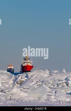 Detroit, Michigan, USA. 26th Januar 2022. Das Schiff der kanadischen Küstenwache Samuel Risley führt die Algocanada, einen Öl-/Chemietanker, durch Eis auf dem Lake St. Clair, wenn sie den Detroit River betreten. Das kalte Wetter in der Region hat an einigen Orten zu Eisstaus und Versandproblemen geführt. Quelle: Jim West/Alamy Live News Stockfoto