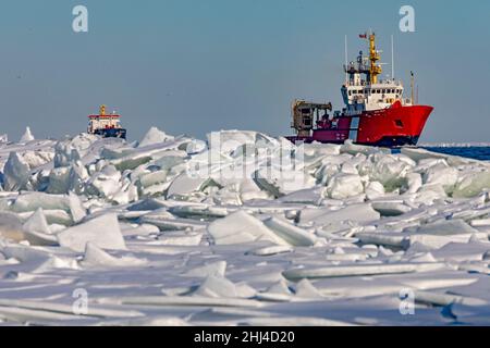 Detroit, Michigan, USA. 26th Januar 2022. Das Schiff der kanadischen Küstenwache Samuel Risley führt die Algocanada, einen Öl-/Chemietanker, durch Eis auf dem Lake St. Clair, wenn sie den Detroit River betreten. Das kalte Wetter in der Region hat an einigen Orten zu Eisstaus und Versandproblemen geführt. Quelle: Jim West/Alamy Live News Stockfoto