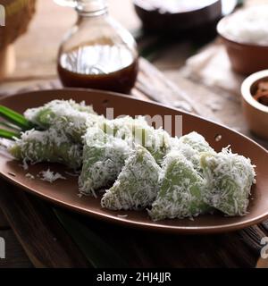 Lupis, indonesischer traditioneller Snack aus klebriges Reis, verpackt mit Bananenblatt, Shape Triangle serviert mit flüssigem Palmzucker und geriebener Kokosnuss Stockfoto