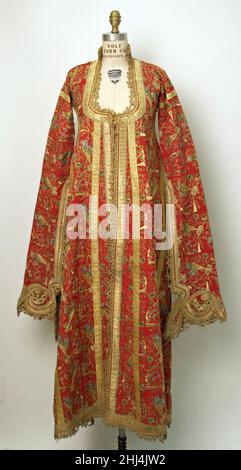 Uçetek Entari oder Dreirock Robe ca. 1870s–Anfang des 20th. Jahrhunderts Diese üçetek entari oder Dreirock Robe hat einen tiefen Ausschnitt und lange Ärmel mit aufwendig verzierten Enden. Es ist charakteristisch für das modische Outfit einer osmanischen Frau aus dem späten 19. Jahrhundert und wird von Frauen der Mittel- und Oberschicht zu besonderen Anlässen getragen. Die hängenden Ärmel dieser Robe sind nur vom Achselbereich bis zum Ellenbogen gezäunt, wodurch sich das Futter aus fein gemusterter und bestickter türkisfarbener Wolle zeigt und einen farbenfrohen Kontrast zum Rot des Hauptstoffes bildet. Das Hemd, das unter getragen wurde Stockfoto