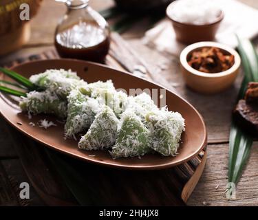 Lupis, indonesischer traditioneller Snack aus klebriges Reis, verpackt mit Bananenblatt, Shape Triangle serviert mit flüssigem Palmzucker und geriebener Kokosnuss Stockfoto