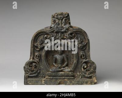 Meditierender Buddha mit der in einer Nische thronenden Almenschale ca. Ende des 10th.–Anfang des 11th. Jahrhunderts Indien (Bihar) dieser meditierende Buddha mit einer Almenschale ist wahrscheinlich der Amitabha Buddha in Form eines der Medizin-Buddhas, wie z. B. Bhaisajyaguru. Ein gehörntes Monstergesicht (Kirtimukha) mit einer Perlenschnur, die aus seinem Kiefer herauskommt, bietet eine schützende Präsenz über dem meditierenden Buddha, der von einem perlenumrandeten Nimbus umrahmt wird. Laub und zwei Lotusblumen füllen den Bogen. Dieses architektonische Relief ist ein falscher Fensterantefix aus einem buddhistischen Monument aus der Pala-Zeit. Meditierender Buddha mit Almosenschale E Stockfoto