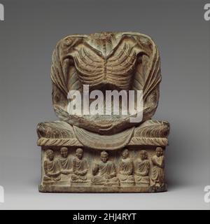 Fasten Buddha Shakyamuni 3rd–5th Jahrhundert Pakistan (alte Region von Gandhara) Nachdem Shakyamuni in Bodhgaya die Erleuchtung erreicht hatte, meditierte und fastete er 49 Tage lang. So bezieht sich die Darstellung als ausgemergelter Verkünder auf seine Erleuchtung und seinen Status als yogischer Asket, der die ultimative Kontrolle über seinen Körper hat. Andere Merkmale, die sich auf seine Erleuchtung beziehen, sind das Kusha-Gras, auf dem er sitzt, und die Szene auf der Basis, die Buddhas erste Predigt in Sarnath zeigt. Fastender Buddha Shakyamuni 38119 Stockfoto