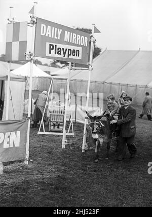 Ein Kind, das auf einem Esel am Daily Mirror Playpen bei der Altrincham-Landwirtschaftsausstellung vorbeireitet. Altrincham, Trafford, Greater Manchester. 23rd. Oktober 1957 Stockfoto