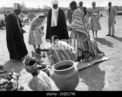 Königin Elizabeth II. Besucht das Modelldorf bei der Kinderkundgebung auf der Kaduna-Rennbahn mit Maaman Bida (Bildungsminister), links, der ihrer Majestät auf der Straße verschiedene Holzfiguren zeigt, ist der Premierminister der nördlichen Region. Sardauna von Sokoto während des königlichen Besuches in Nigeria am 3. Februar 1956 Stockfoto
