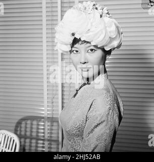 Tsai Chin, Schauspielerin und Hauptrolle in West End, spielt The World of Suzie Wong, im Prince of Wales Theatre, London, fotografiert Modelling Hats in Dolores, Großhandelsmüllern der Welbeck Street, Marylebone, London, 19th. November 1959. Stockfoto