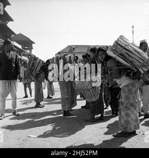 Nepalesische Frauen, die hier auf dem Durbar Square, Katmandu, im Bergreich von Nepal, gesehen wurden, nachdem sie mit Feuerholz aus den Bergen herabgekommen waren und an ihren Rücken anzündet hatten. Februar 1961 l Stockfoto