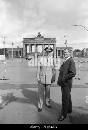 General Bruce C Clarke, Oberbefehlshaber der US-Armee in Europa am Brandenburger Tor mit dem West-Berliner Bürgermeister Willy Brandt, drei Tage nach Beginn des Baus der Berliner Mauer. Im Hintergrund ist eine schwergepanzerte Wasserstrahlwerfer aus Ostdeutschland mit einer auf die beiden Männer trainierten Strahldüse zu sehen. 16th. August 1961. Stockfoto