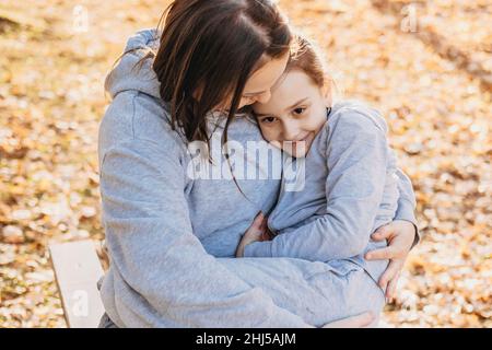 Mutter verbringt Zeit mit ihrer Tochter im Freien im Park, Mutter schaukelt ihre müde Tochter. Viel Spaß mit der Familie. Familienbetreuung. Lächelndes, glückliches Kind Stockfoto