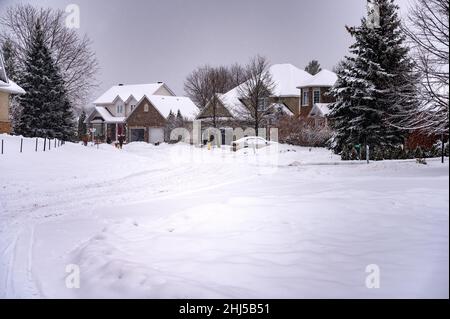 Vorstadtstraße nach dem Schneesturm, aber leichter Schnee fällt immer noch Stockfoto
