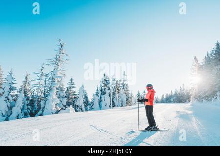 Skifahren. Skimorträt der Frau Alpin Skifahrer Haltungen Skier tragen Helm, coole Skibrille und Hardshell Winterjacke und Skihandschuhe an kalten Tag in Stockfoto