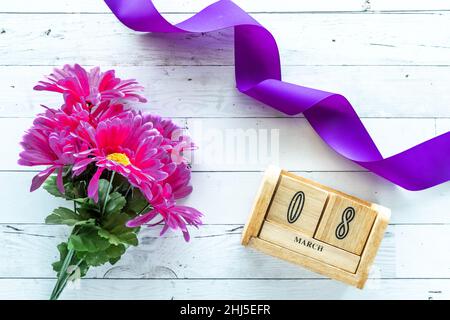 Helle Fuchsia-Blumen mit violettem Band zum Internationalen Frauentag. Stockfoto