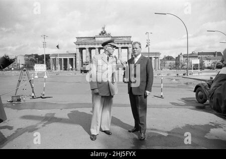 General Bruce C Clarke, Oberbefehlshaber der US-Armee in Europa am Brandenburger Tor mit dem West-Berliner Bürgermeister Willy Brandt, Drei Tage nach dem Bau der Berliner Mauer ist im Hintergrund eine schwergepanzerte Wasserstrahlwerfer aus der DDR mit einer auf die beiden Männer trainierten Strahldüse zu sehen. 16th. August 1961. Stockfoto