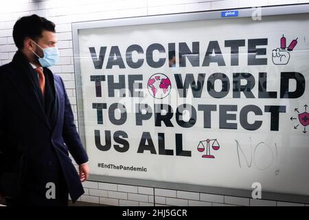 London, Großbritannien. 26th Januar 2022. Ein Mann mit einer Maske kommt an einem Schild vorbei, auf dem Impfungen in Westminster Station in London gefördert werden. Ab dem 27th. Januar wird die Verwendung von Gesichtsmasken an allen öffentlichen Orten nicht mehr obligatorisch sein, da die Bedrohung durch die Omicron-Variante von Covid-19 nachlässt. Kredit: SOPA Images Limited/Alamy Live Nachrichten Stockfoto