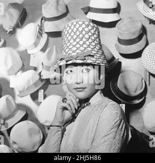 Tsai Chin, Schauspielerin und Hauptrolle in West End, spielt The World of Suzie Wong, im Prince of Wales Theatre, London, fotografiert Modelling Hats in Dolores, Großhandelsmüllern der Welbeck Street, Marylebone, London, 19th. November 1959. Stockfoto