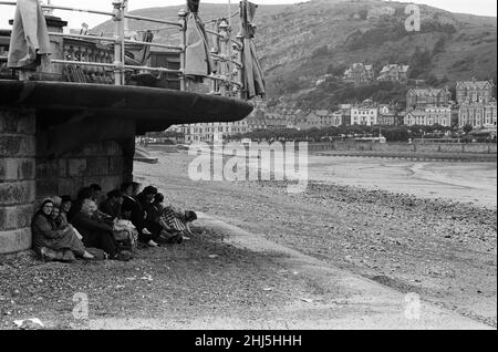 Llandudno, eine Küstenstadt in Conwy County Borough, Wales. Urlauber, die sich vor dem schlechten Wetter schützen. 16th. Juli 1958. Stockfoto