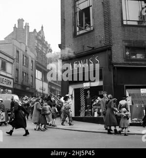 Cowboys und Indianer vom Billy Smarts Circus fahren in die Stadt und führen vor dem lokalen Geschäft Lewis's einen Laufkampf durch. Davy Crocket Smart bekämpft den Angriff von einem Fenster im Obergeschoss aus. Hanley, Staffordshire. 21st. März 1956. Stockfoto