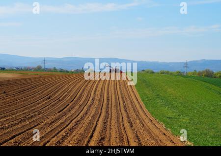 Ein Traktor am Horizont eines frisch zubereiteten Kartoffelfeldes. Stockfoto