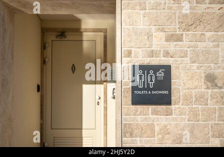 Toilette und Dusche. Öffentliche Toiletten und Duschen mit einem Schild. Außen, Fassade der Strandtoilette und Duschen. Gäste-Duschmöglichkeit Schild am Publi Stockfoto